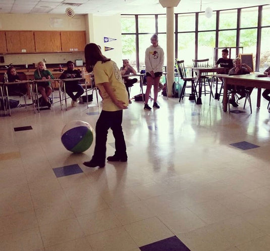 A student simulates showing a hog using a beach ball in the school classroom as fellow students and FFA advisor look on.