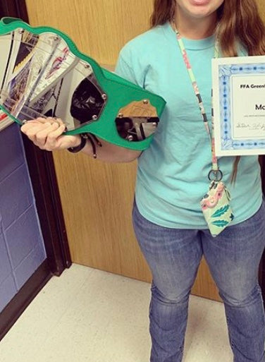 Student holding professional wrestling styled belt as student of the month