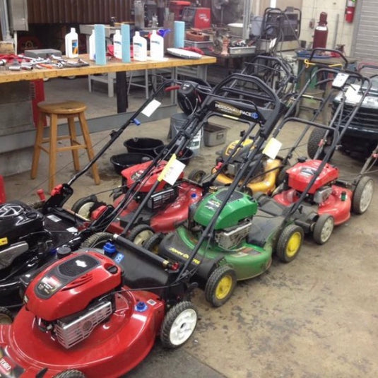 A collection of used lawnmowers are lined up in the Ag shop ready for servicing by high school students.